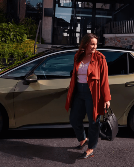 donna-sorridente-vicino-auto-volkswagen-sfondo-casa